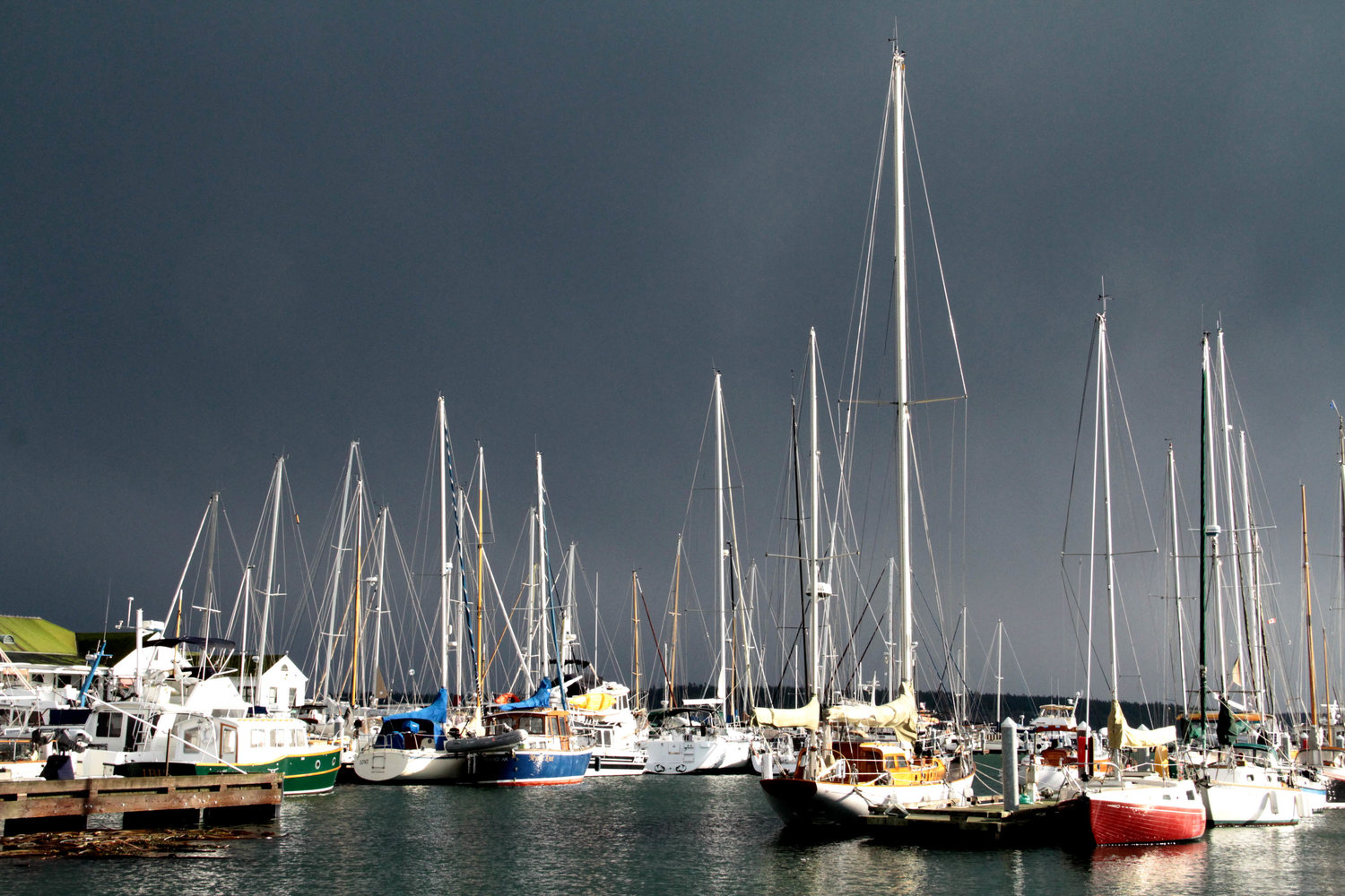 Sailboats at the Point Hudson Marina are lighted by a sun-break in Monday's storm as dark clouds darken Port Townsend Bay.